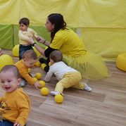 Escola Infantil Apolo 10 niños y maestra en salón con decoración amarilla
