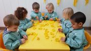 Escola Infantil Apolo 10 niños con papeles de color amarillo