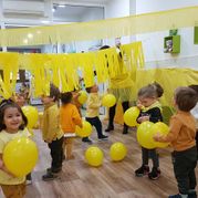 Escola Infantil Apolo 10 niños con globos y papeles amarillos