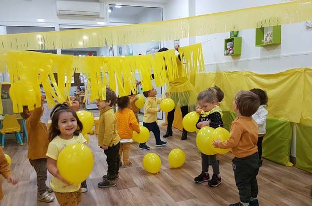  niños con globos y papeles amarillos