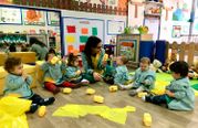 Escola Infantil Apolo 10 maestra y niños armando figuras con papeles amarillos