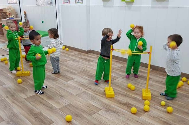  niños jugando con pelotas amarillas