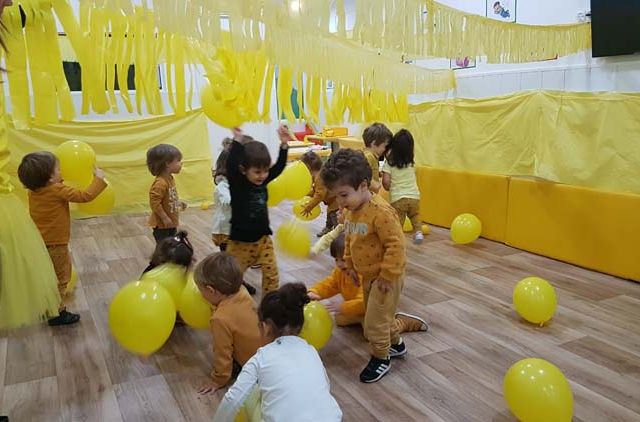  niños jugando con globos amarillos